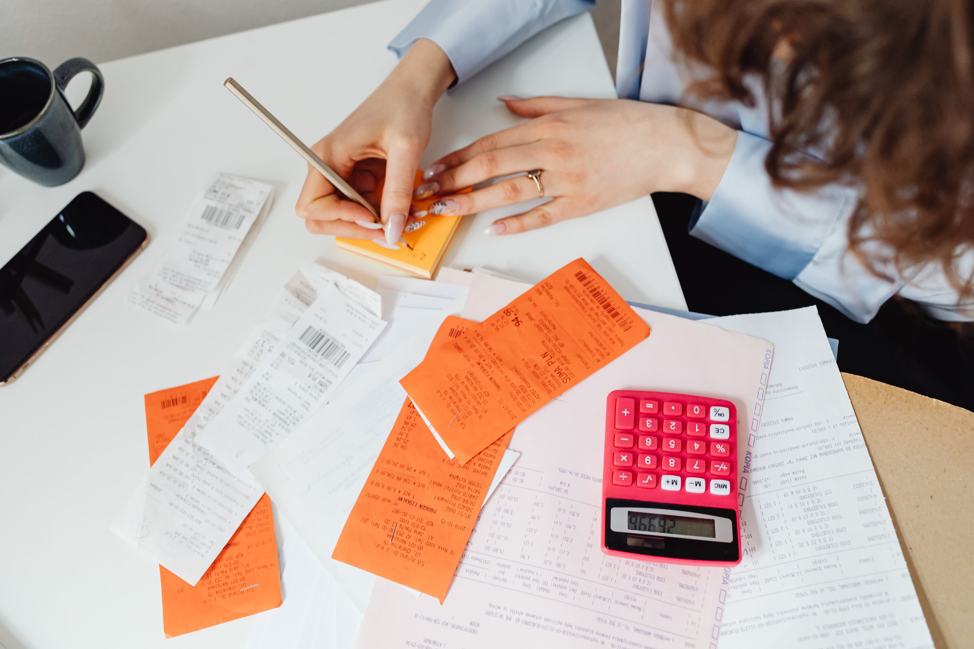 Sorting a pile of paper fuel receipts by hand with a calculator at month's end